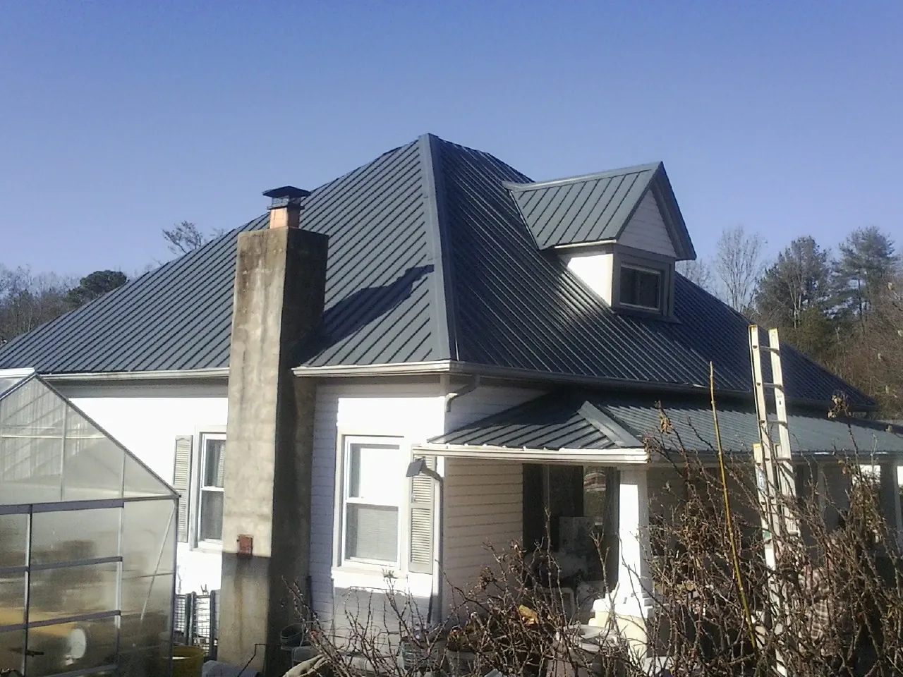 Dark blue standing seam metal roof on a white farmhouse with dormer — Slate & Tile Roof Repair by Roofing Brothers in Woodway