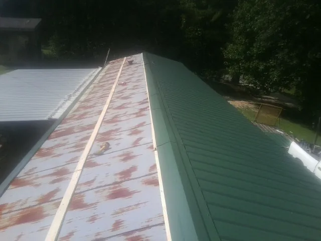 Old rusted panels beside newly installed green metal roofing — Wind Damage Roof Repair by Roofing Brothers in Woodway