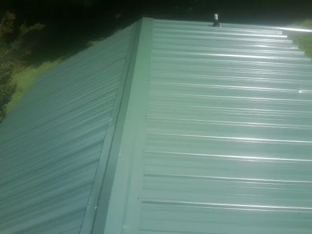 New green metal panels meeting at the ridge of a roof — Flat Roof Repair work by our crew in Woodway