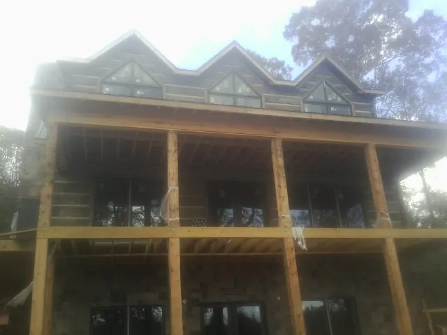 Dormers and porch framing on a large log home under construction — Roof Coating work by our crew in Woodway