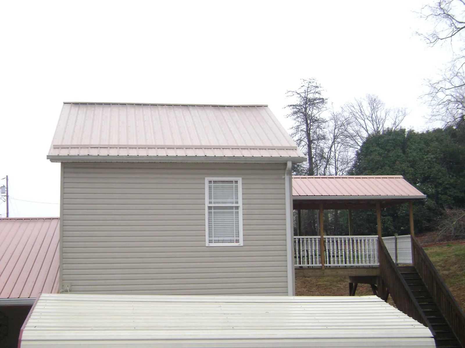 Tan metal roofs on a two story addition and attached porch, from a Roof Replacement job in Woodway