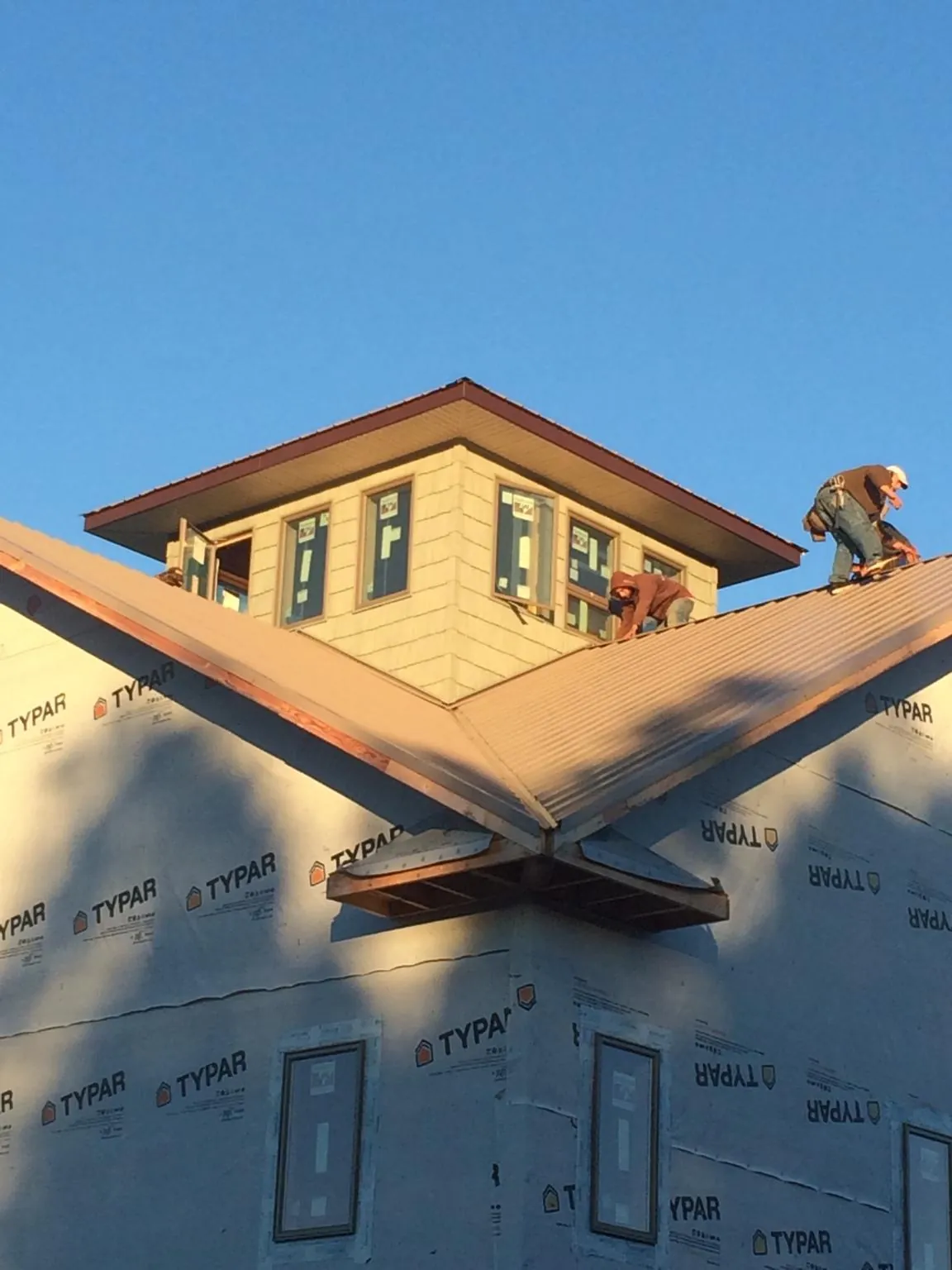 Roofers working around a rooftop cupola on a new metal roof at sunset — Roof Waterproofing in Woodway by Roofing Brothers